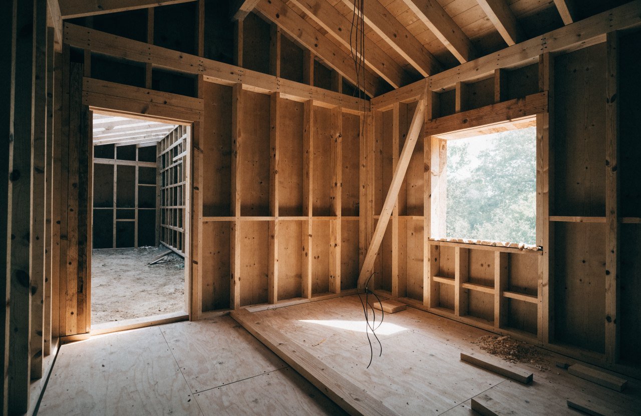 The inside of an unfinished building shell with exposed stud walls and roof rafters